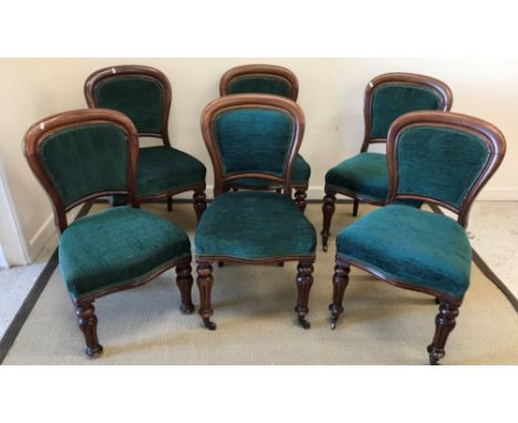 A set of six Victorian dining chairs with green upholstered backs and seats, raised on turned and reeded baluster front legs 