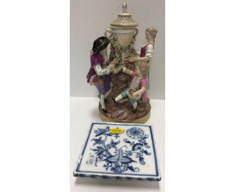 A late 19th Century Meissen figure group as a man and woman with seated child arranging a floral swag upon a two handled urn 