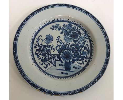 An early 19th Century Delftware plate decorated in the chinoiserie style with vase of flowers and fence, unmarked, edge nibbl