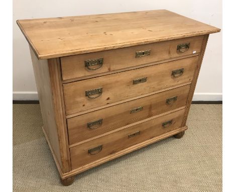 A 19th Century French pine commode, the plain top over four long drawers with brass drop handles raised on turned and carved 