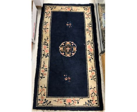 A vintage Chinese rug, the central panel set with floral decorated circular spray on a dark blue ground, within a stepped blu