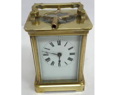 A circa 1900 French lacquered brass cased carriage clock, the enamelled dial with Roman numerals, raised on bracket foot base