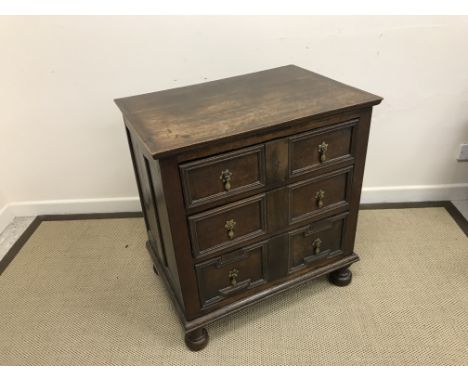 An oak chest in the 17th Century manner, the plain top over three long drawers with applied moulded edges and brass teardrop 