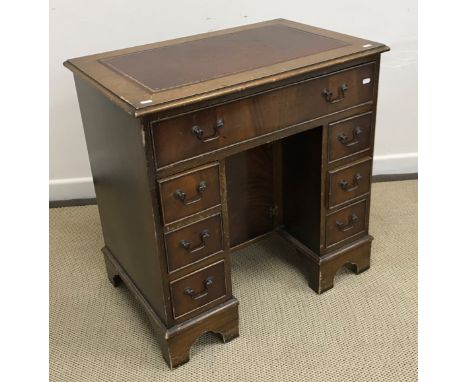 A mahogany kneehole desk in the Georgian style, the top with tooled and gilded leather insert within a moulded edge over a si