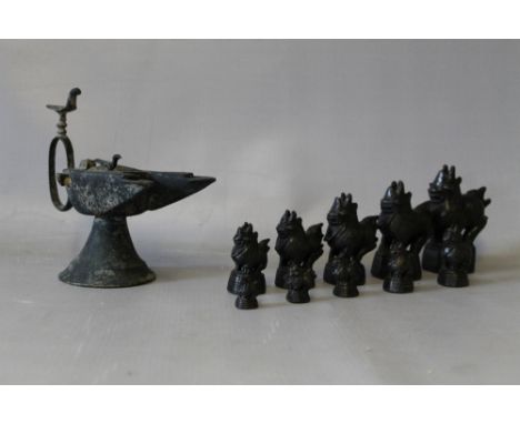 AN ISLAMIC / MIDDLE EASTERN OIL LAMP, with bird finial and two spouts, together with a graduated set of 10 Burmese / Thai cas