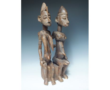 A TRIBAL ART CARVED WOODEN FIGURE DEPICTING A MAN AND A WOMAN SEATED, carved detail throughout, H 55 cm