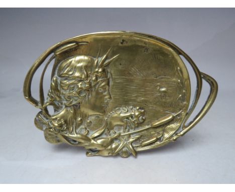 A BRASS ART NOUVEAU TRINKET DISH, embossed with a female head in side profile against a riverside background scene, W 19 cm