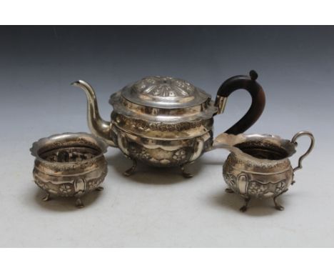 AN UNMARKED WHITE METAL CONTINENTAL THREE PIECE TEA SERVICE, decorated with typical Asian village scenes, engraved to top of 