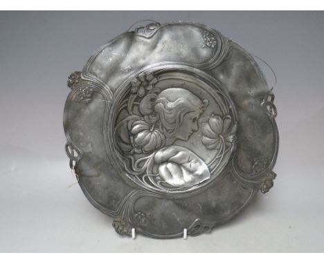 AN ART NOUVEAU CIRCULAR PEWTER DISH FOR RESTORATION- POSSIBLY WMF, embossed with a female head in side profile amongst flower