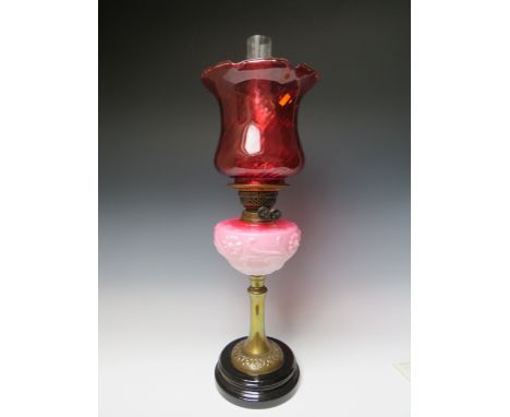 AN ART NOUVEAU STYLE OIL LAMP, having graduated pink opaque pressed glass reservoir, twin burner, cranberry glass shade with 