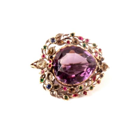 An unusual silver brooch set with a large amethyst to centre with diamond, emerald, ruby and sapphire set surround