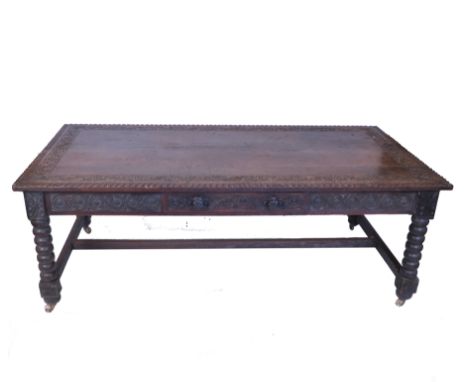 An oak dining table, with a scroll and gadroon carved border with a similarly carved frieze under, with drawers around, raise