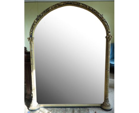 A large gilt arched over mantel mirror, in the Gothic style, with columns with scroll capital and leaves, mirror size approxi