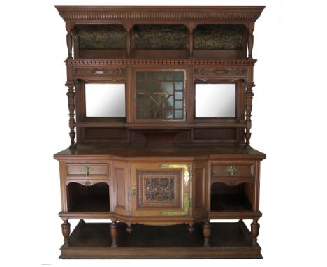 A late 19th century oak sideboard, having a glazed central cupboard flanked by mirrors with a concave embossed canopied shelf