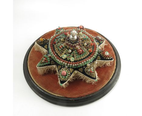 A 19th century star shaped pin cushion, decorated with bands of coloured beads pinned to cushion, width 13ins, on a velvet li