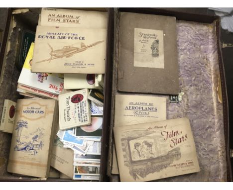 A vintage suit case containing a quantity of cigarette cards and cigarettes card albums.