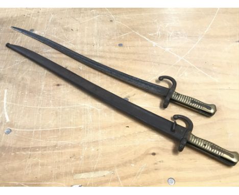 A 19th century French bayonet with brass handle, dated 1868 with a scabbard, and another identical bayonet also dated 1868 wi