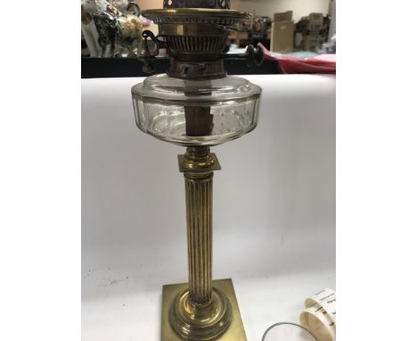 A brass oil lamp with shade and chimney.