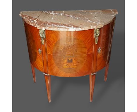 A French bow fronted gilt metal mounted commode, the variegated marble top above two inlaid drawers flanked by similar cupboa