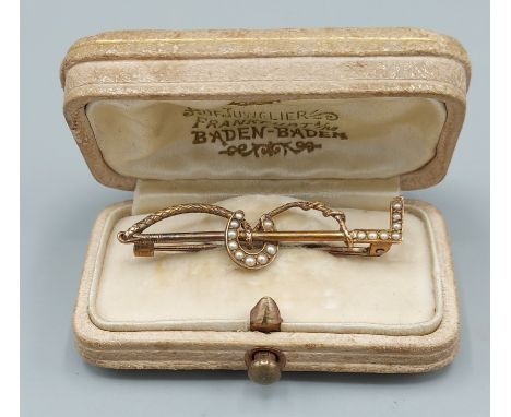 A yellow Gold brooch in the form of a riding crop and horse shoe, set with pearls, 4cms long, 3.1gms