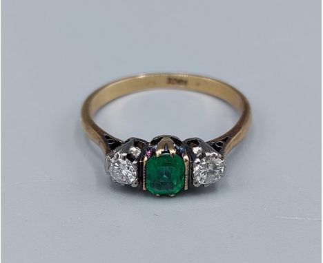 An 18ct gold Emerald and Diamond three stone ring set with a central Emerald flanked by Diamonds, claw set, 2.7gms, ring size