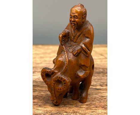 A Japanese hand carved netsuke of a elderly gentleman riding an ox. [5cm in length] 