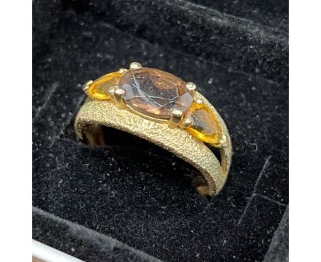 A ladies 9ct yellow gold three stone ring, Brown Smokey centre stone with two citrine style shoulder stones. [Ring size N] [3