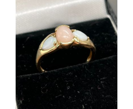 A Ladies 9ct yellow gold ring set with a centre pink opal and off set by two white opals to the shoulders. [Ring size Q] [2.1