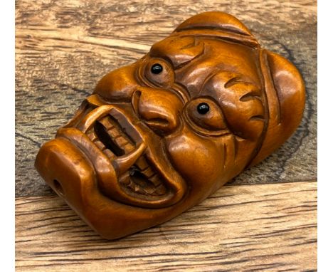 A Japanese hand carved Hannya mask netsuke. Designed with black bead eyes and signed. [5cm in length] 