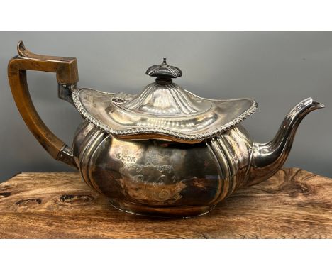 A London silver ornate tea pot with wooden handle. Engraved with Initial 'H' to the front panel. Maker Robert Pringle &amp; S