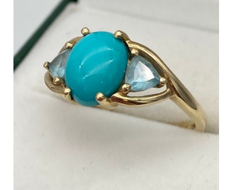 A Ladies 9ct yellow gold ring set with a large Turquoise centre stone, off set by two aqua coloured stones to the shoulders. 