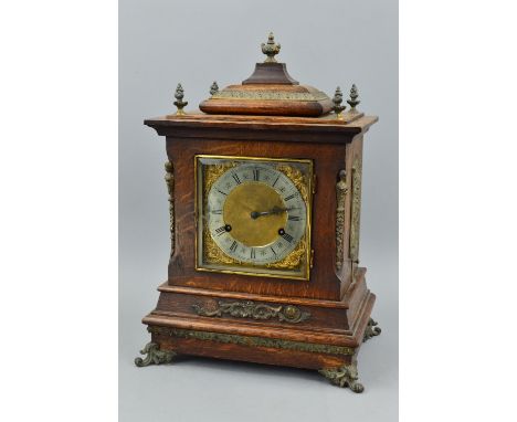 A LATE VICTORIAN OAK CASED BRACKET CLOCK, the architectural top with five finials, bevelled glass door below enclosing a silv