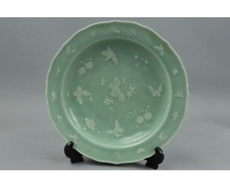 A CHINESE CELADON DISH, of wavy circular form, enamelled with white butterflies and flowers, bears blue mark to base, diamete