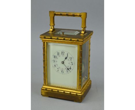AN EARLY 20TH CENTURY GILT BRASS CARRIAGE CLOCK, the handle, four columns, pediment and foot cast with bobbin turned decorati