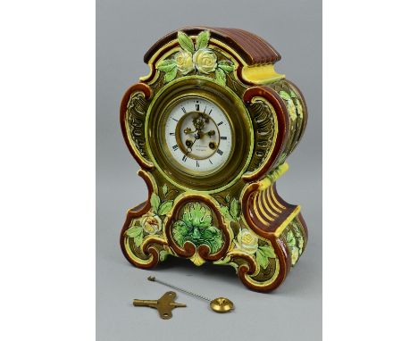 A LATE 19TH CENTURY MAJOLICA CASED MANTEL CLOCK, the case of domed and scrolled form moulded in relief with flowers, grotesqu