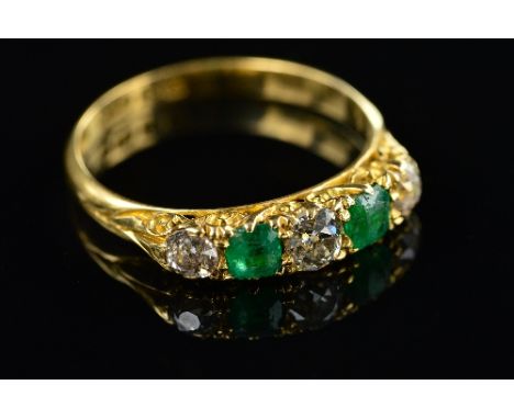 AN 18CT EDWARDIAN EMERALD AND DIAMOND HALF HOOP RING, carved scroll sides and settings, three old European cut diamonds, grad