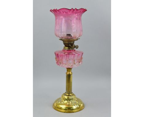 A LATE VICTORIAN/EDWARDIAN BRASS BASED OIL LAMP, the cranberry glass shade with acid etched floral decoration, cranberry rese