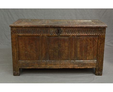 AN 18TH CENTURY OAK COFFER, triple panel hinged top, the interior with left hand end shelf, the front with chip carved frieze