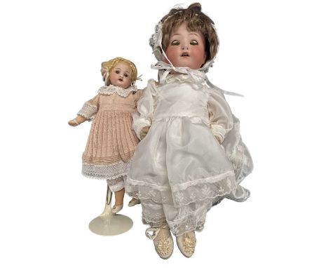 A pair of Heubach Koppelsdorf bisque head dolls, to include: - Young girl in white dress and bonnett with sleep eyes and brow