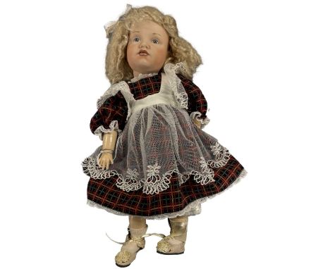 A bisque head Kammer and Reinhardt doll with painted blue eyes and curled blonde hair. Wearing tartan dress with net apron, m