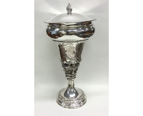 OMAR RAMSDEN: A massive tapering silver cup and cover attractively decorated with scrolls and balls to textured body and lift