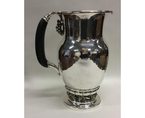 GEORG JENSEN: A massive silver ewer / pitcher attractively decorated with vines on textured body to ebony handle. Numbered 40