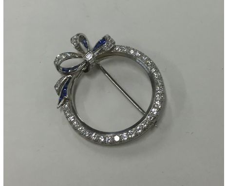 An attractive sapphire and diamond bow brooch of circular form set in platinum. Approx. 9.5 grams. Est. £500 - £600.