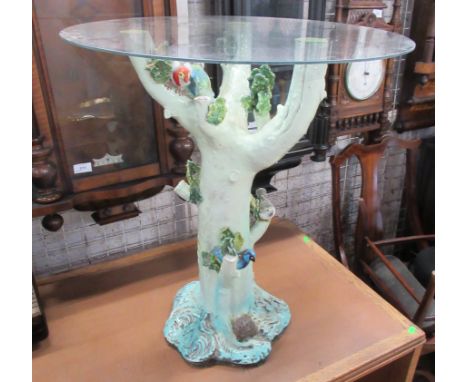 A circular topped table, the base formed as a tree trunk with birds, in porcelain, with circular glass top