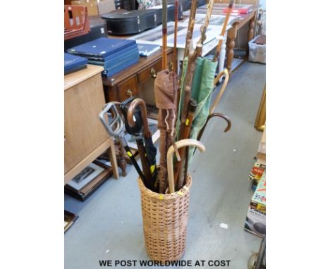 A wicker stick stand with various sticks including a measuring stick, silver-mounted examples,, cane fishing rods etc