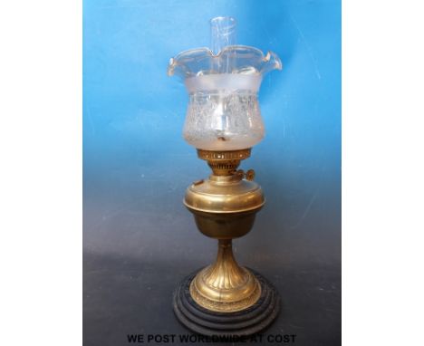 A brass oil lamp with Duplex burner and etched glass shade, standing on a turned ebonised base