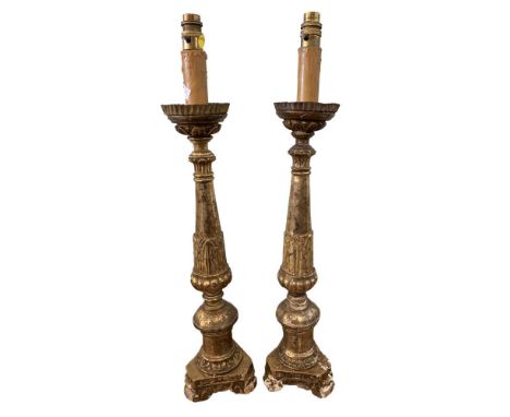 A pair of Continental carved giltwood pricket candlestick lamps, with crenellated tin plate drip pans, converted to electrici
