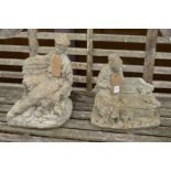 Two reconstituted stone garden ornaments modelled as a man and a women seated on a bench.