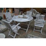 A circular hardwood folding garden table with a set of four folding armchairs.