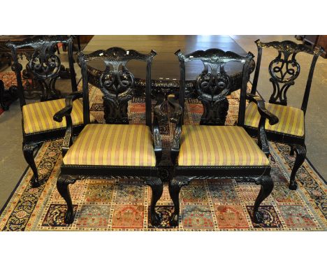 A set of fourteen ebonised Chippendale style dining chairs with drop in seats, all standing on cabriole legs and ball and cla
